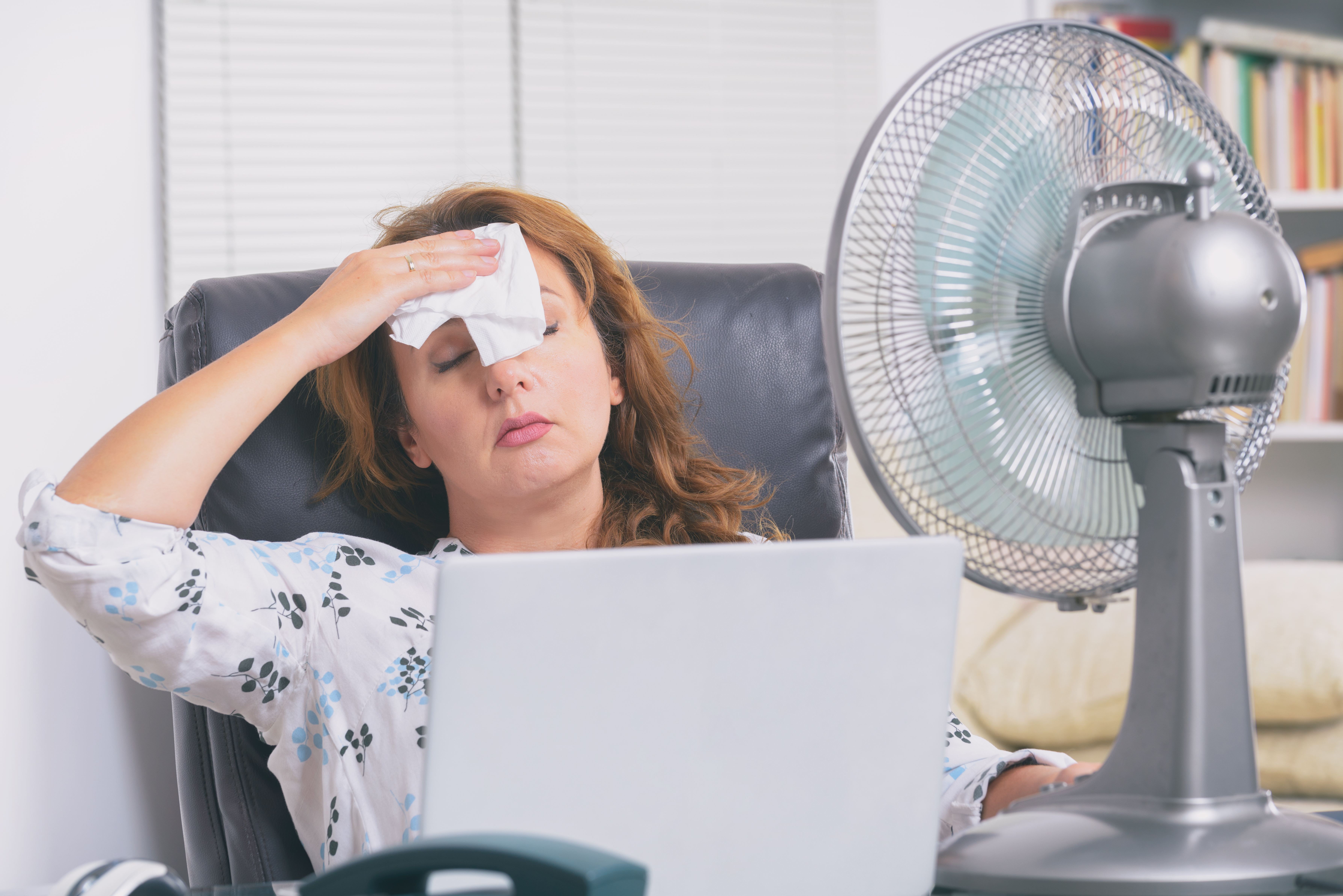 Woman tries to cool down in hot office