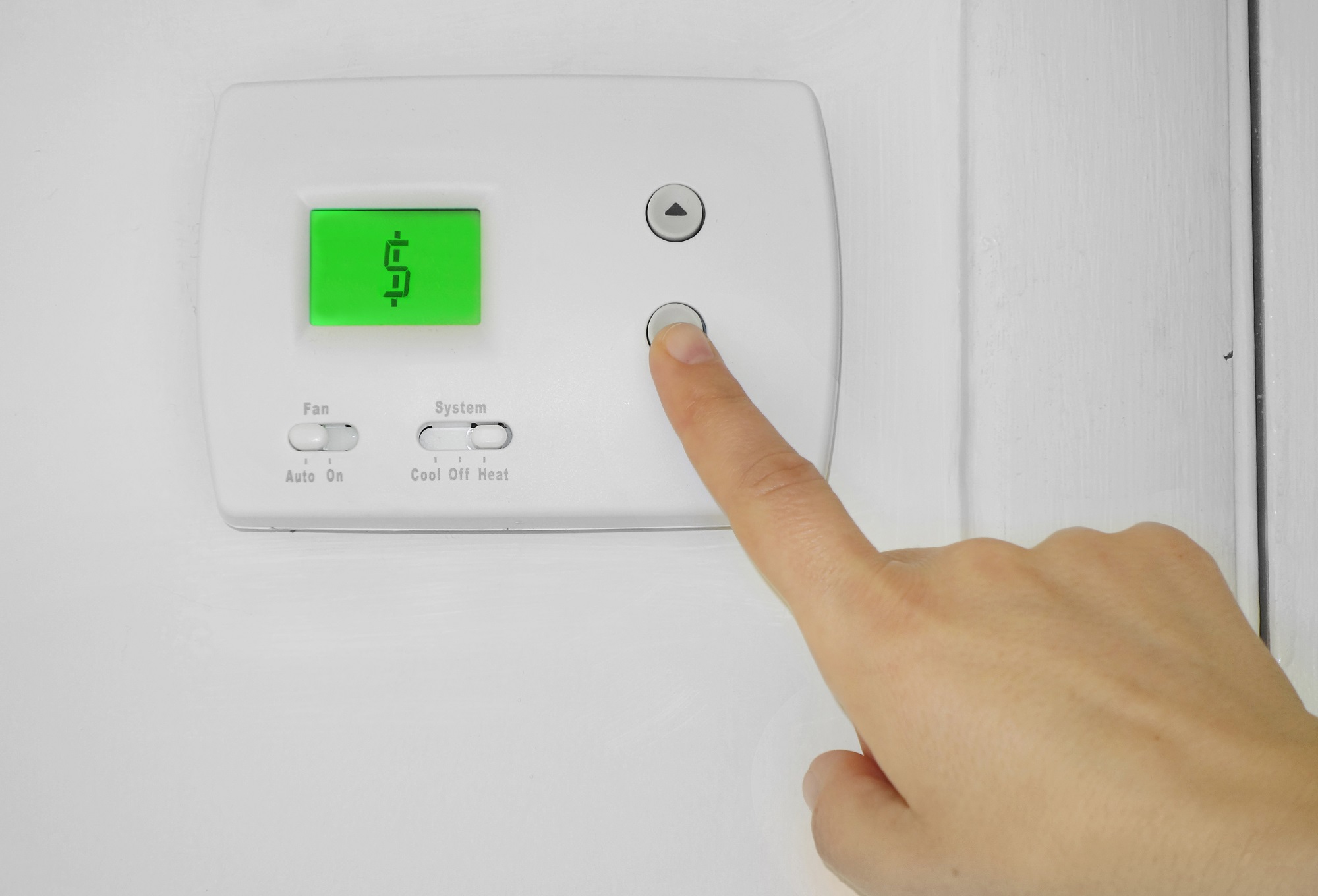 thermostat cost Person adjusting a wall thermostat with dollar sign symbol on the display